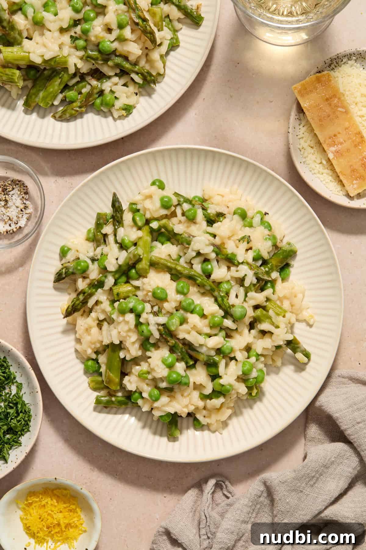 Creamy Spring Risotto with Peas and Asparagus 13 Plate with risotto with peas and asparagus with dishes surrounding.