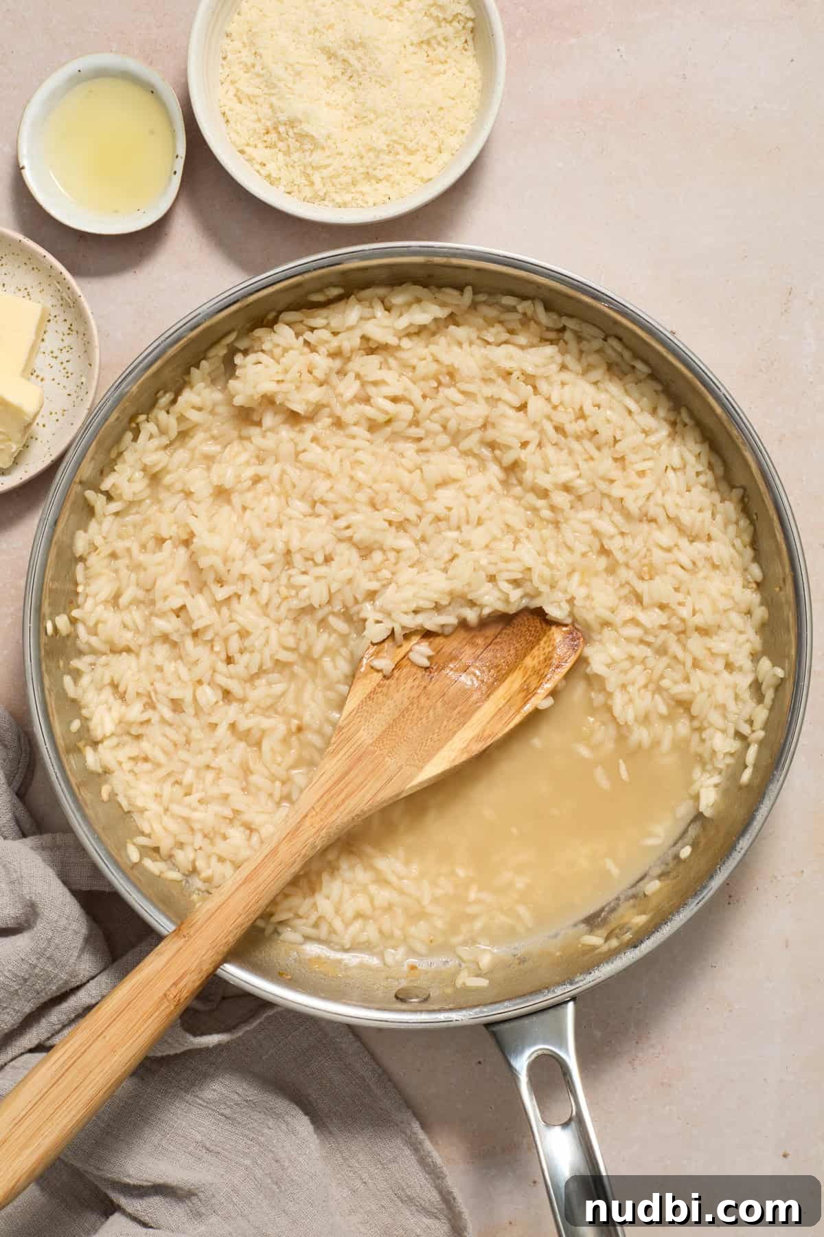 Creamy Spring Risotto with Peas and Asparagus 9 Broth added to risotto in skillet with wood spoon.