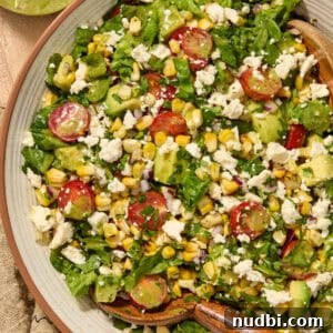 Salad with grilled corn, romaine, avocado, tomato in bowl.
