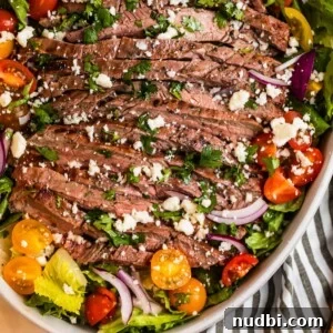 Grilled flank steak salad in dish topped with freshly chopped cilantro and cheese.
