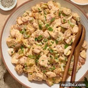 Cajun Potato Salad Recipe with Zesty Dressing and Bacon 11 Serving bowl with potato salad and serving utensils.