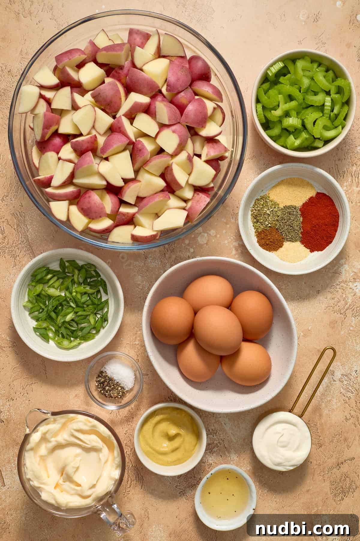 Cajun Potato Salad Recipe with Zesty Dressing and Bacon 3 Potatoes, eggs, celery, mayo and other ingredients arranged on surface.