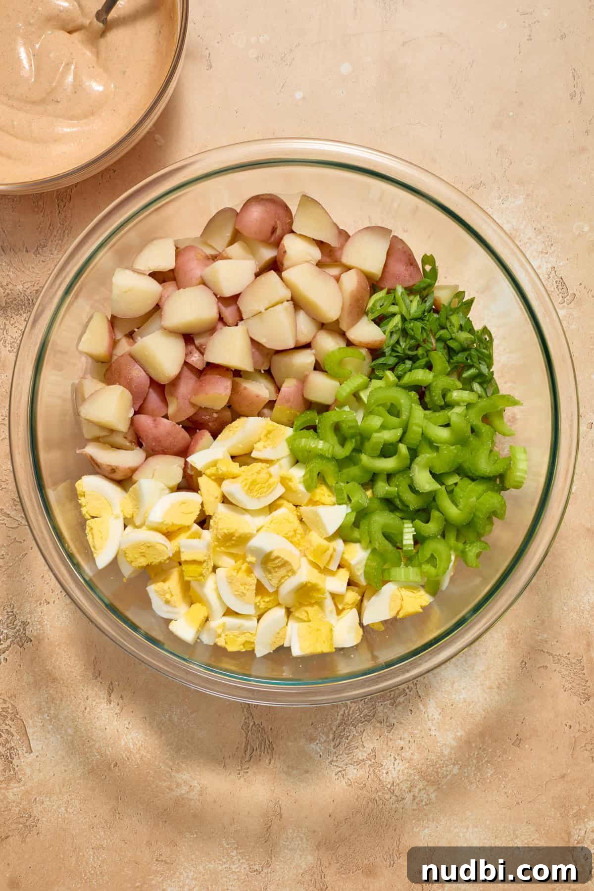 Cajun Potato Salad Recipe with Zesty Dressing and Bacon 8 Boiled potatoes, chopped eggs, celery and onion in glass bowl before tossing.