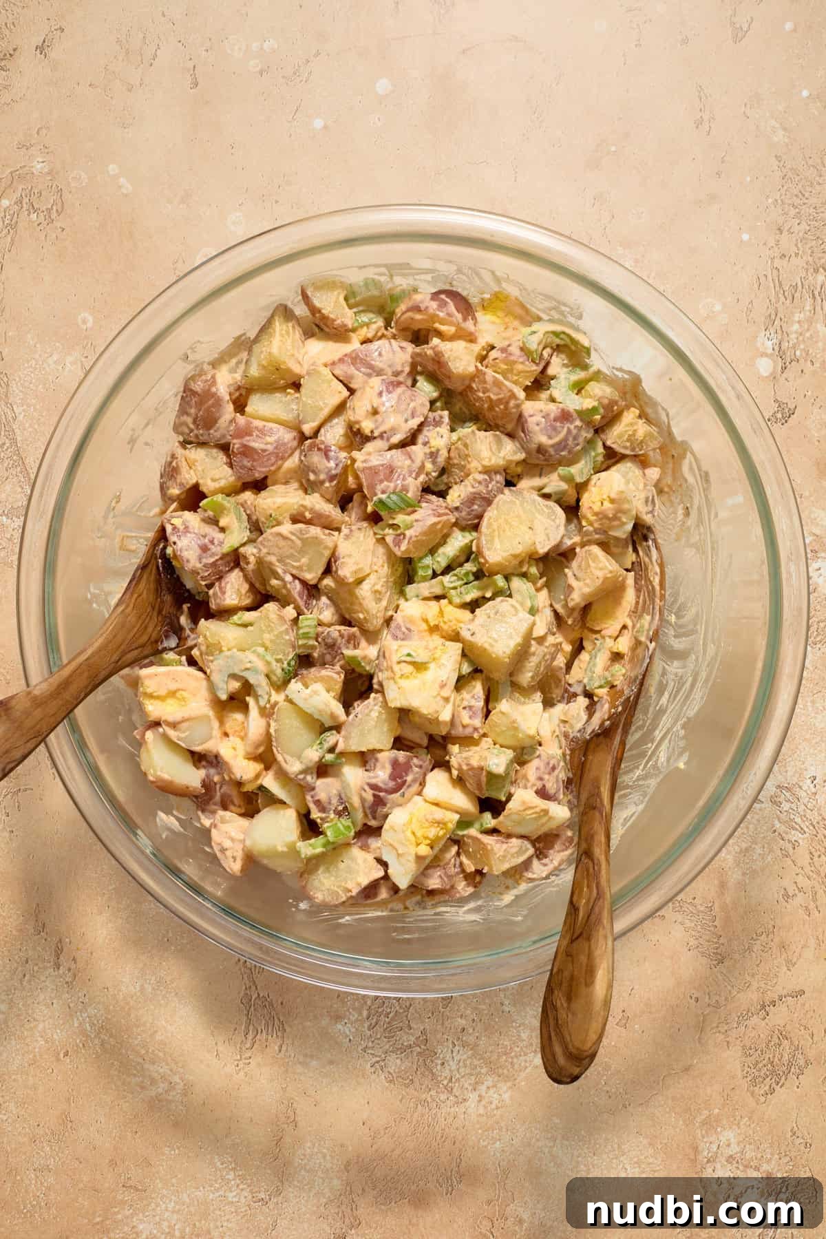 Cajun Potato Salad Recipe with Zesty Dressing and Bacon 9 Cajun potato salad in glass bowl after being tossed with dressing.