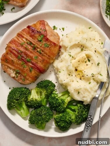 White plate with pork chop dinner including mashed potatoes and broccoli.