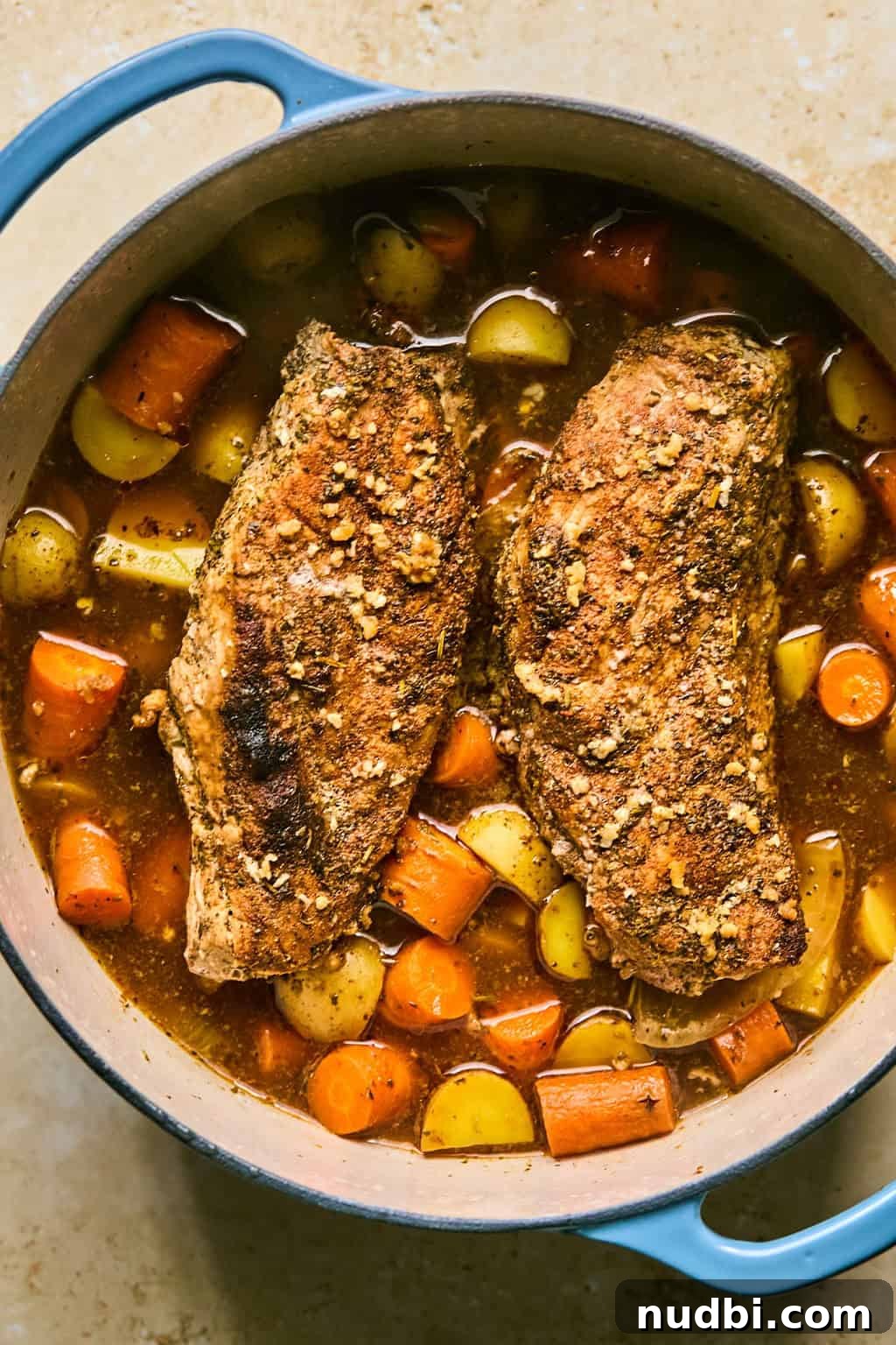 Juicy Pork Tenderloin in a Dutch Oven: Simple Oven-Braised Recipe 5 Cooked and glazed pork tenderloin in pot with carrots and potatoes.