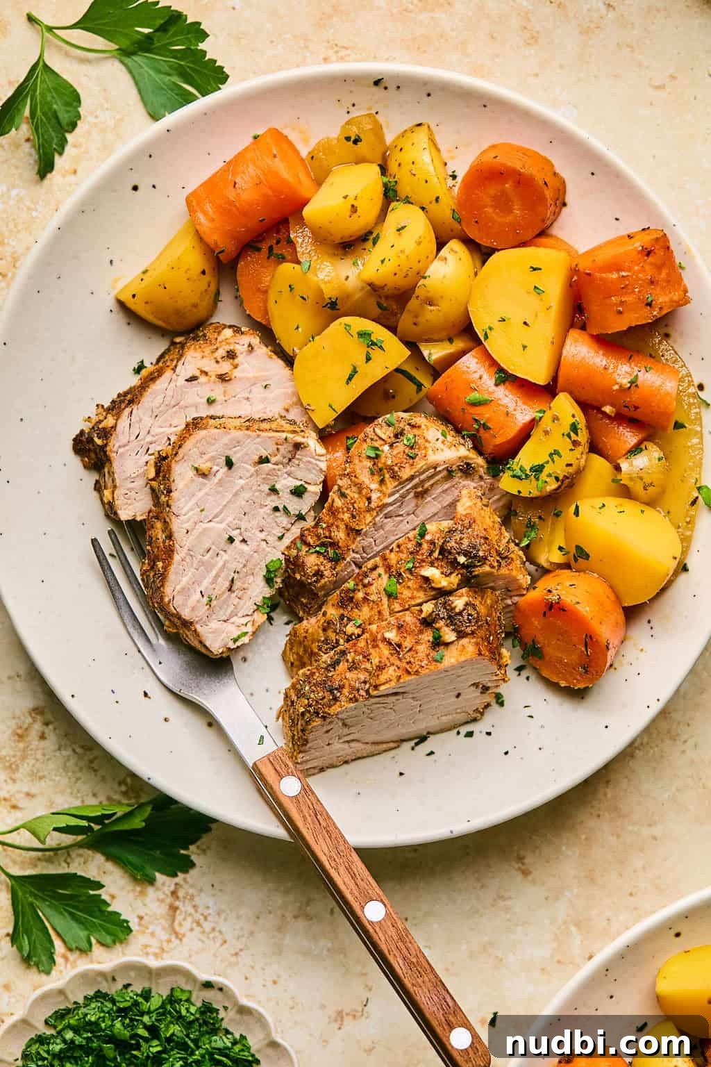 Juicy Pork Tenderloin in a Dutch Oven: Simple Oven-Braised Recipe 6 Plate with sliced pork tenderloin and carrots and potatoes.