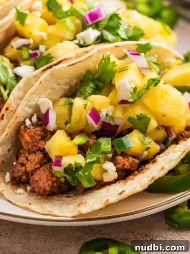 Ground pork tacos in tortillas topped with pineapple, jalapeño and cilantro salsa.