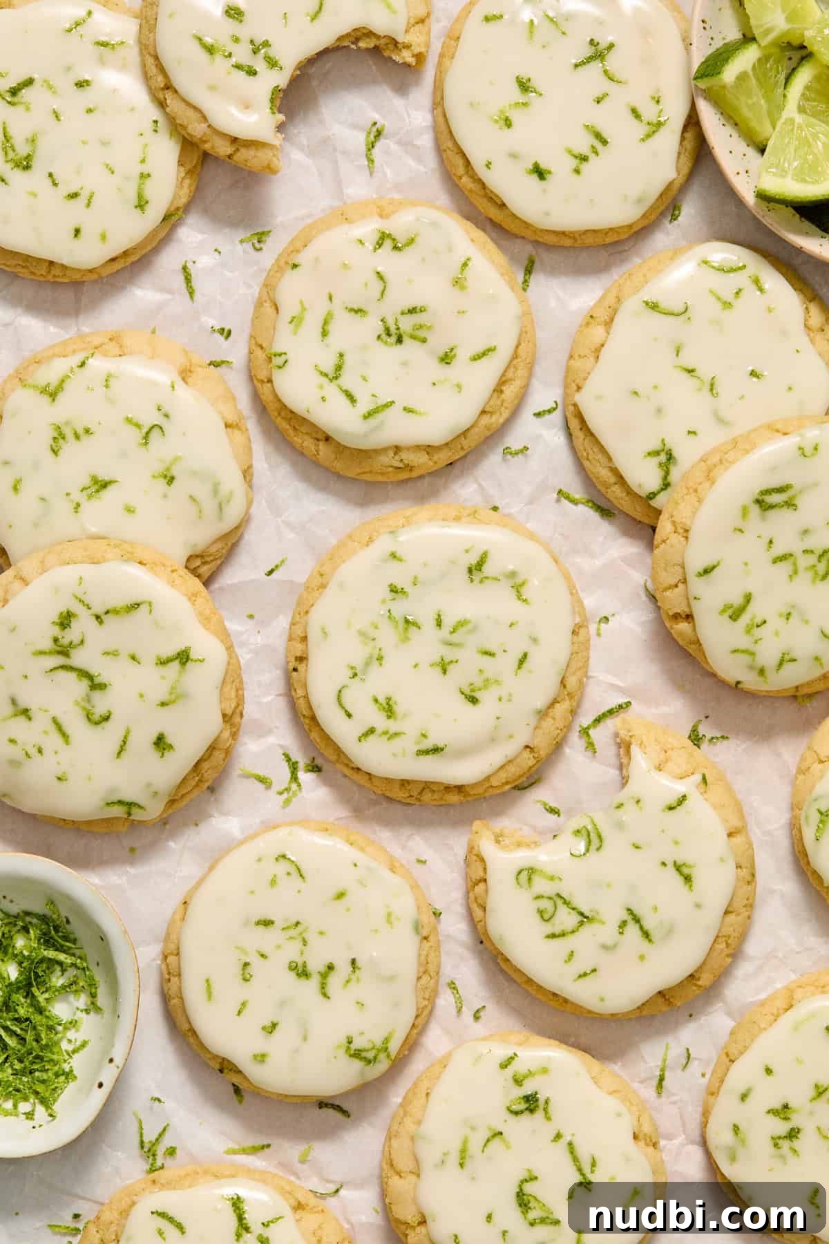 Zesty Key Lime Cookie Recipe for Luscious Citrus Cookies 2 Key lime cookie with lime glaze on counter with other cookies and limes surrounding.