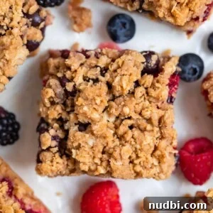Mixed berry bar with oat crumble topping on parchment.