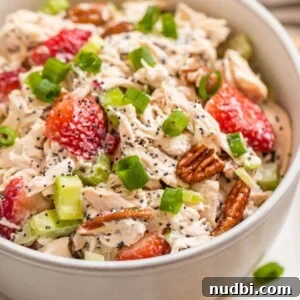 White bowl with strawberry pecan chicken salad topped with green onion and pecans.