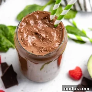 Chocolate raspberry smoothie with avocado and spinach on counter.