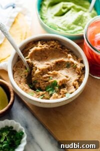 Side Dishes to Serve with Carnitas: 15 Flavor-Packed Pairings 15 Refried beans in bowl with spoon and other dishes surrounding.