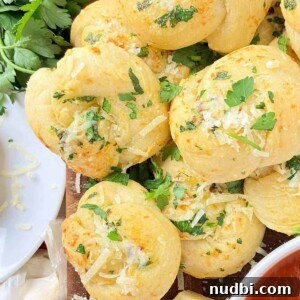 10 Delicious Side Dishes to Serve With Gnocchi 15 Garlic knots on cutting board with freshly chopped parsley.