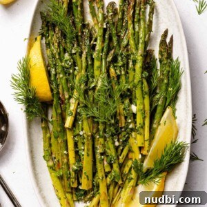 10 Delicious Side Dishes to Serve With Gnocchi 18 Lemon herb roasted asparagus on white plate with lemons.