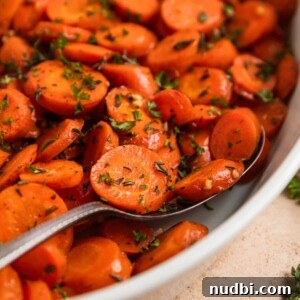 10 Delicious Side Dishes to Serve With Gnocchi 23 Serving spoon scooping into carrots in white dish.