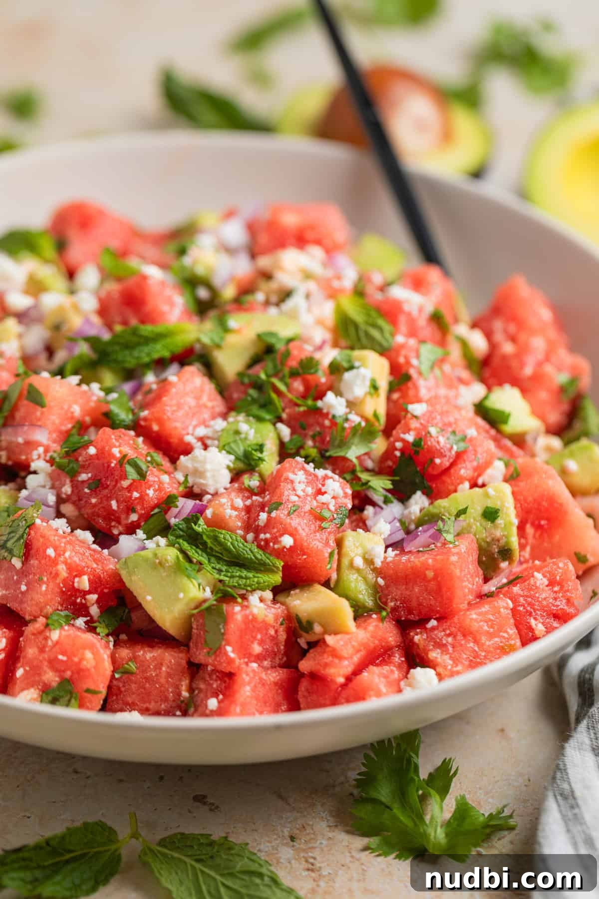 Watermelon and Avocado Salad with Feta and Mint 9 Salad bowl with watermelon, feta and avocado salad with spoon.