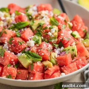 Watermelon and Avocado Salad with Feta and Mint 10 Bowl with watermelon salad with feta and avocado and spoon scooping into it.