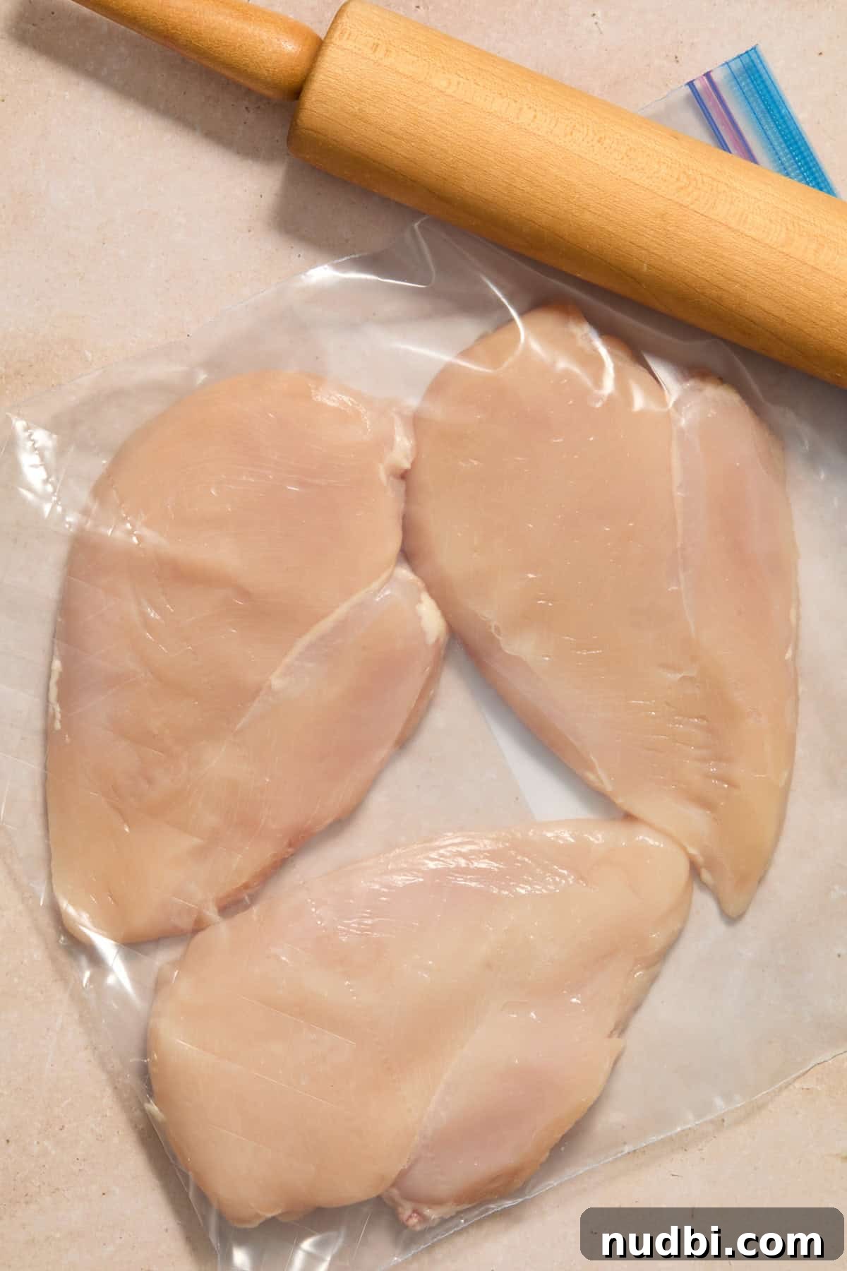 Lemon Pepper Grilled Chicken Recipe – Zesty Weeknight Dinner 5 Chicken pounded in plastic bag with rolling pin.
