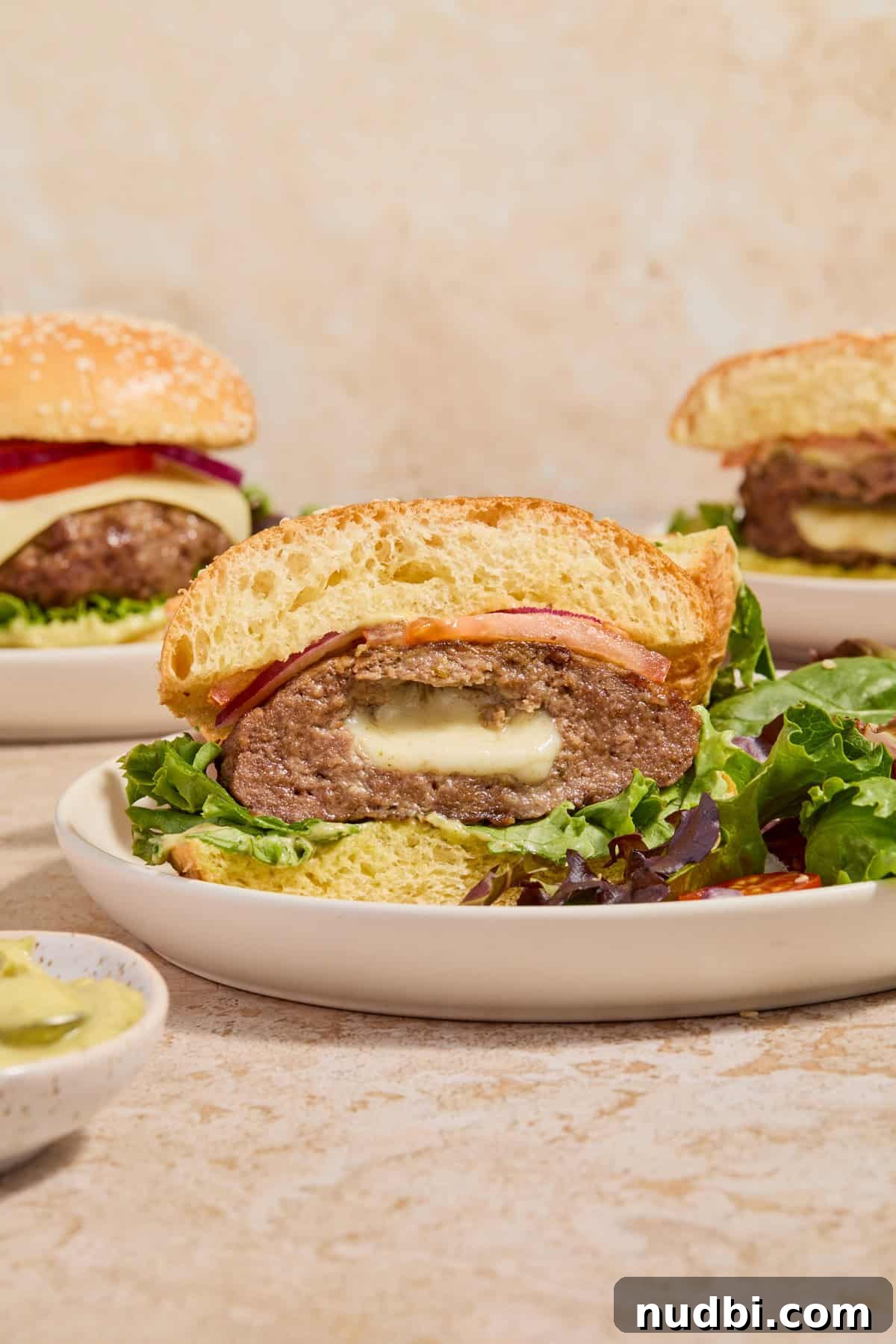 Juicy Mozzarella-Stuffed Burgers with Garlic Herb Buns 11 Mozzarella burger sliced in half with bun and pesto mayo.