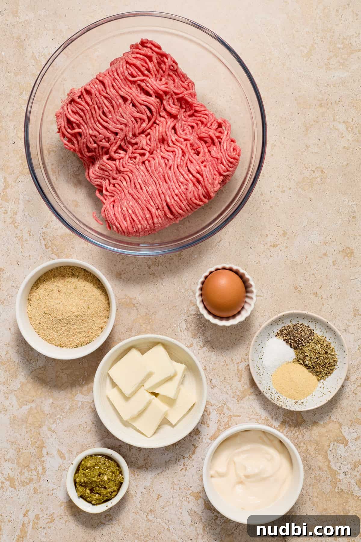 Juicy Mozzarella-Stuffed Burgers with Garlic Herb Buns 4 Ground beef, egg, breadcrumbs and other ingredients arranged on surface.