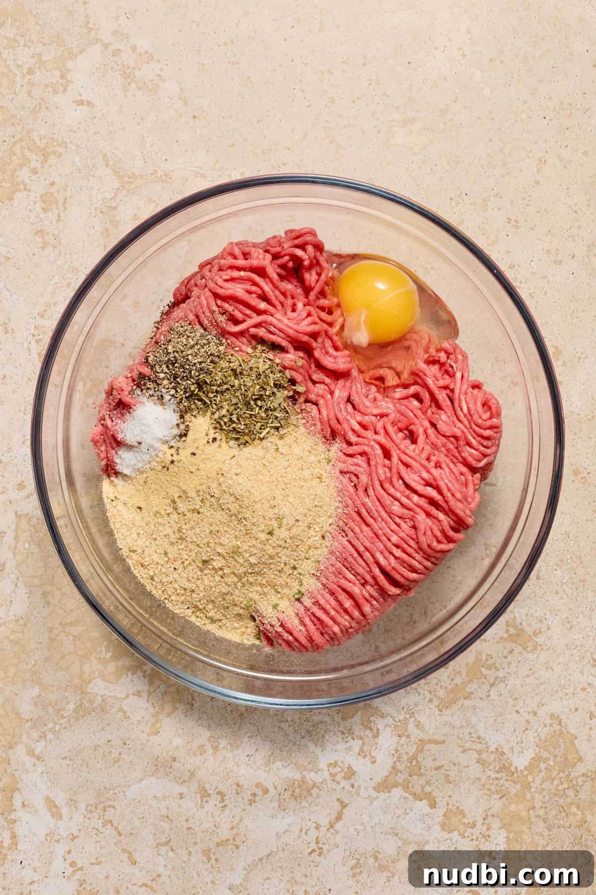 Juicy Mozzarella-Stuffed Burgers with Garlic Herb Buns 5 Ground beef, egg, breadcrumbs and other ingredients in glass bowl.