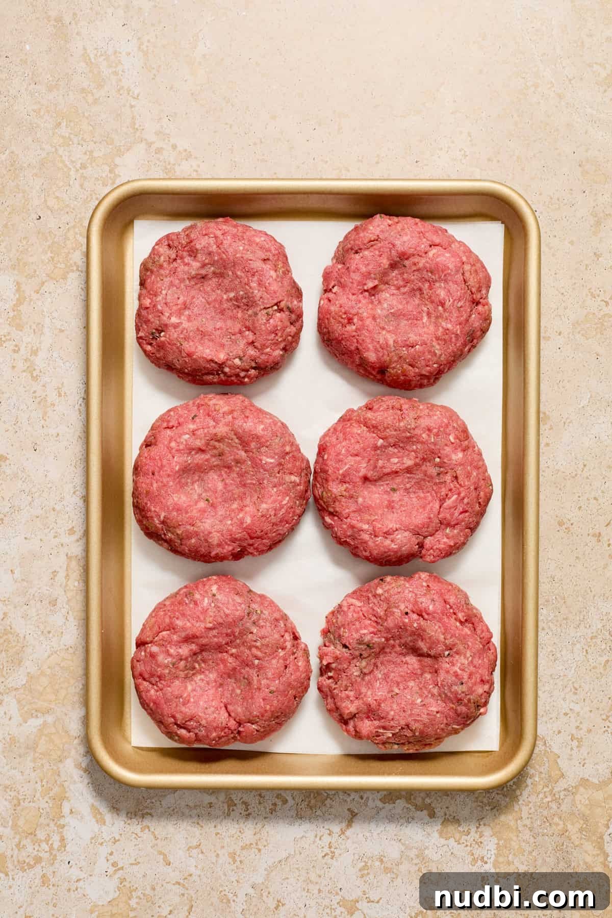 Juicy Mozzarella-Stuffed Burgers with Garlic Herb Buns 9 Mozzarella stuffed hamburgers on parchment lined pan before grilled.