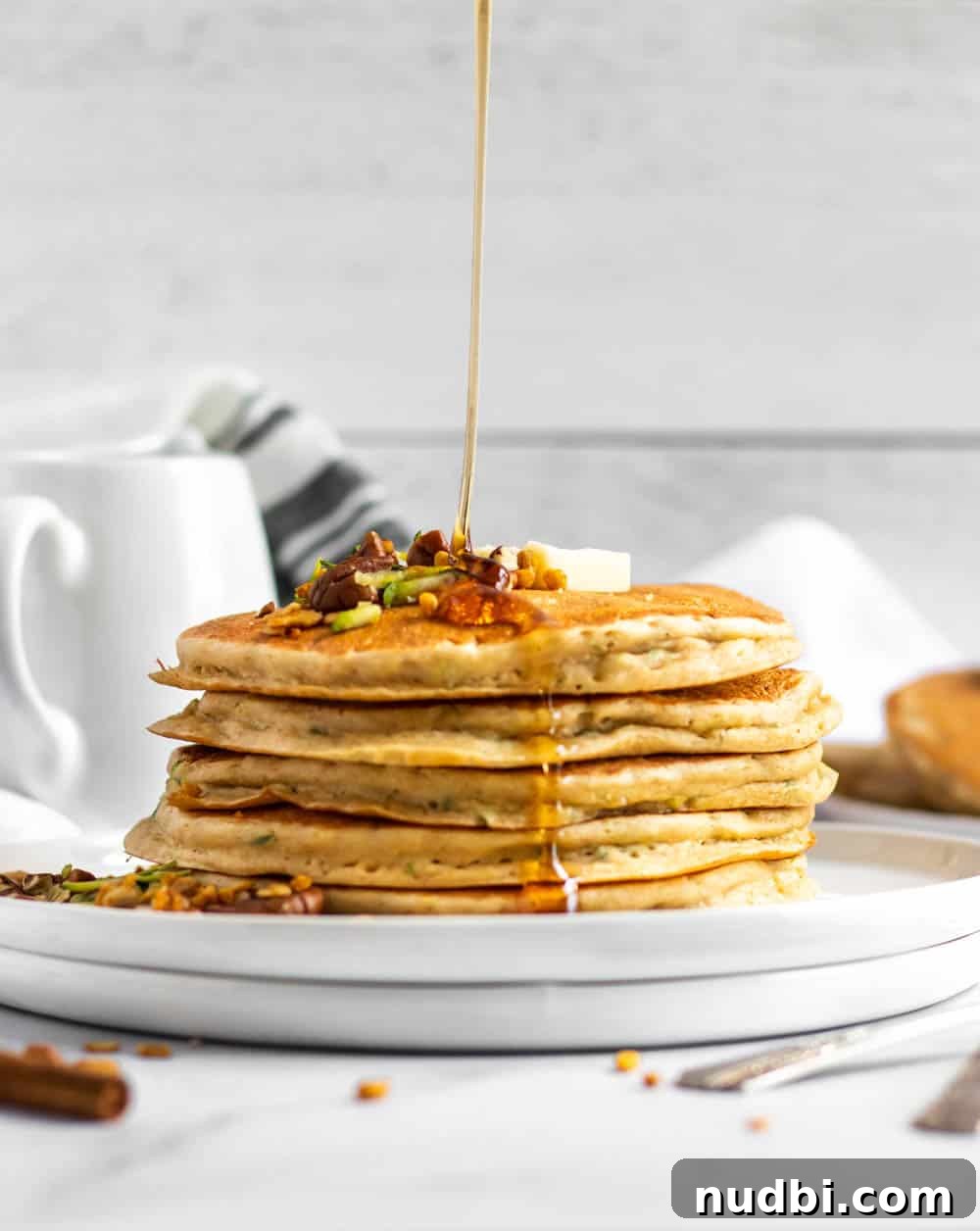 Zucchini Pancakes with Oat Flour — Light, Fluffy & Gluten-Friendly 2 Zucchini pancakes on plate with syrup drizzle.