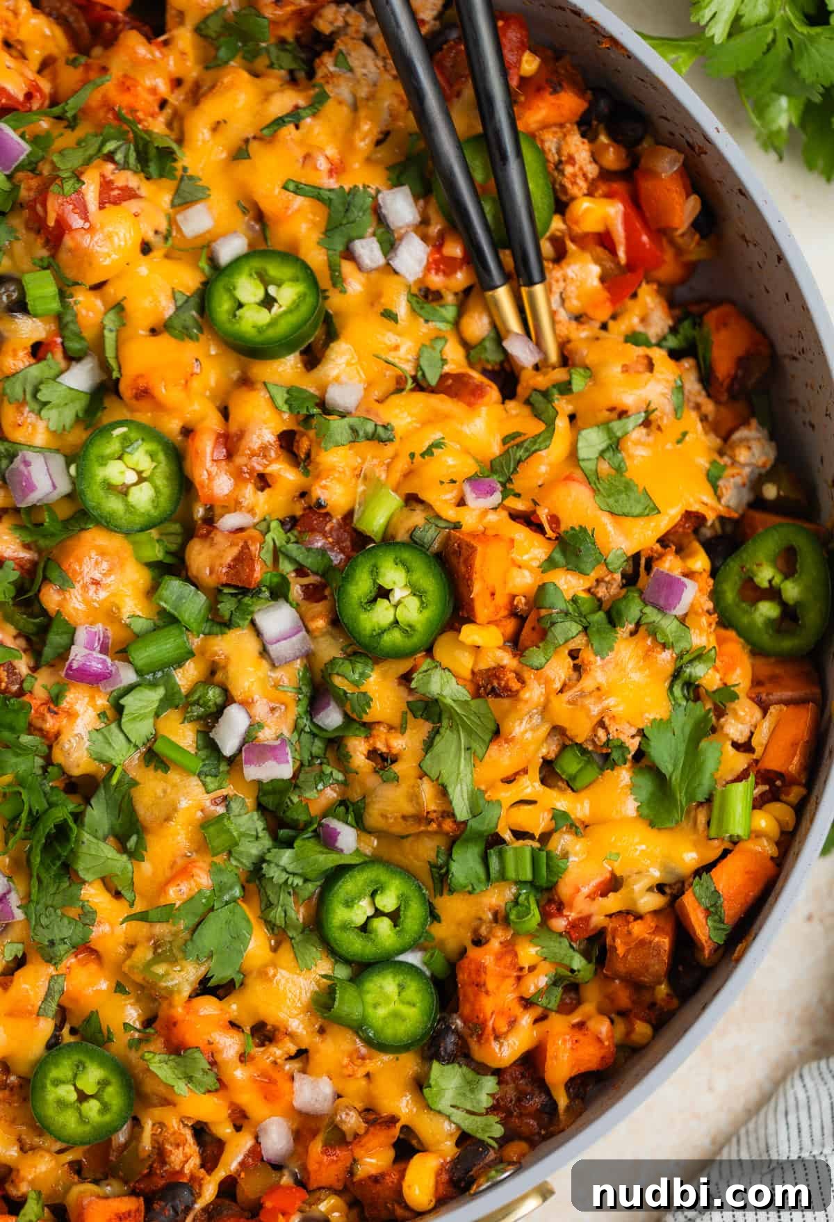 One-Pan Ground Turkey and Sweet Potato Skillet Recipe 11 Skillet with ground turkey and sweet potatoes topped with melted cheese and serving utensils scooping in.