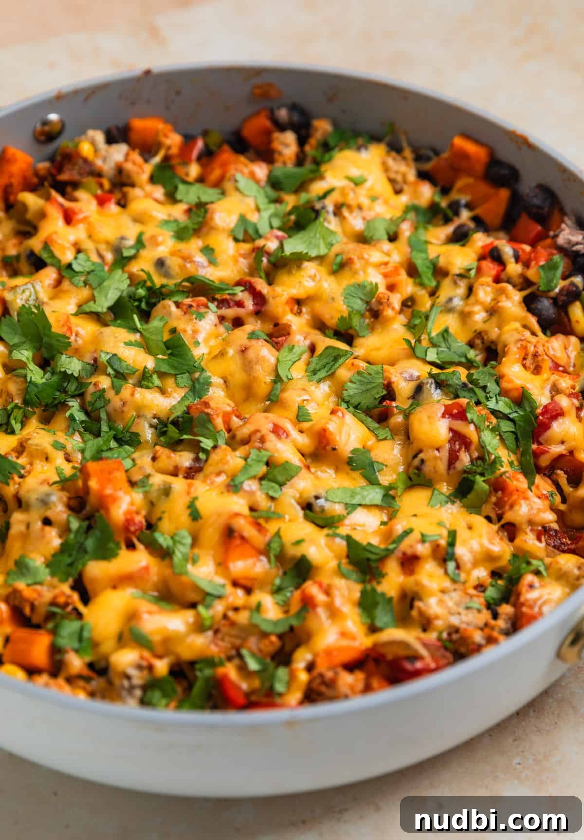 One-Pan Ground Turkey and Sweet Potato Skillet Recipe 10 Cheese melted over top of skillet dinner with chopped cilantro over top.