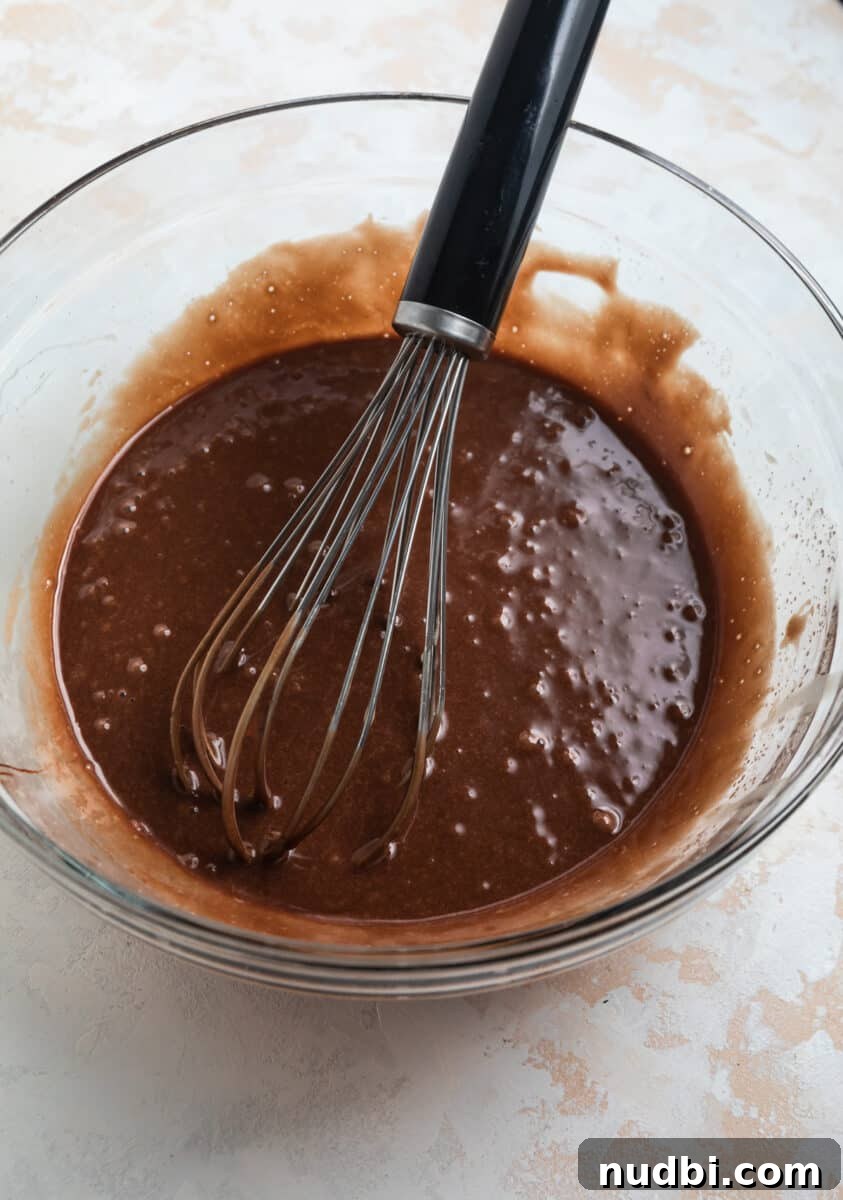 Fudgy Condensed Milk Brownies Recipe with Glossy Caramel Top 4 Chocolate mixture in mixing bowl with whisk.