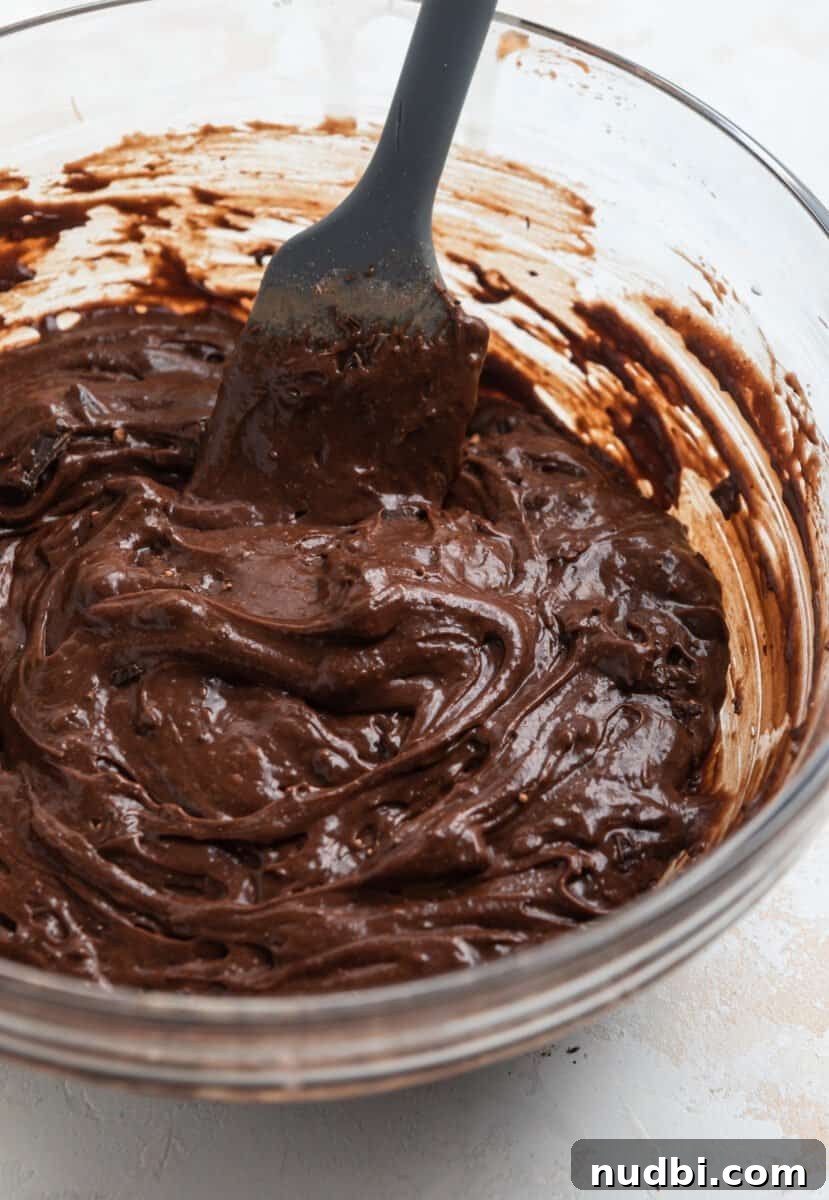 Fudgy Condensed Milk Brownies Recipe with Glossy Caramel Top 5 Condensed milk brownie batter in glass bowl with gray spatula.