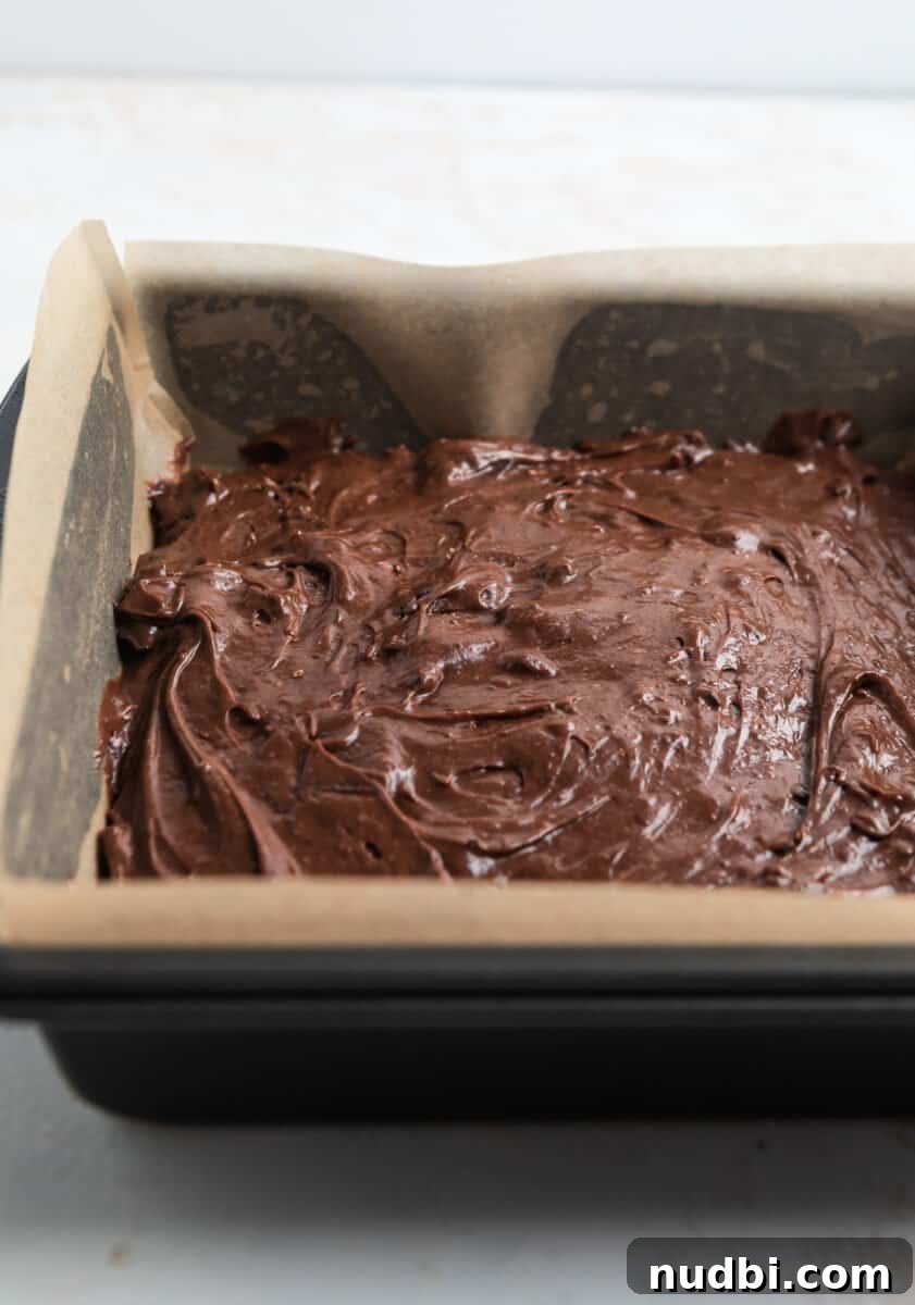 Fudgy Condensed Milk Brownies Recipe with Glossy Caramel Top 6 Brownie batter in 8 inch square baking pan lined with parchment paper.