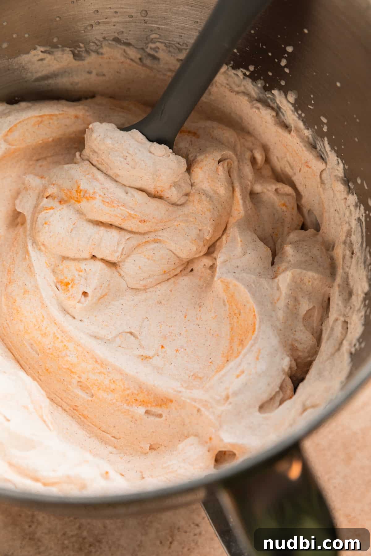 Pumpkin Spice Whipped Cream Recipe — Light & Fluffy Topping 6 Pumpkin spiced whipped cream in bowl with spatula.