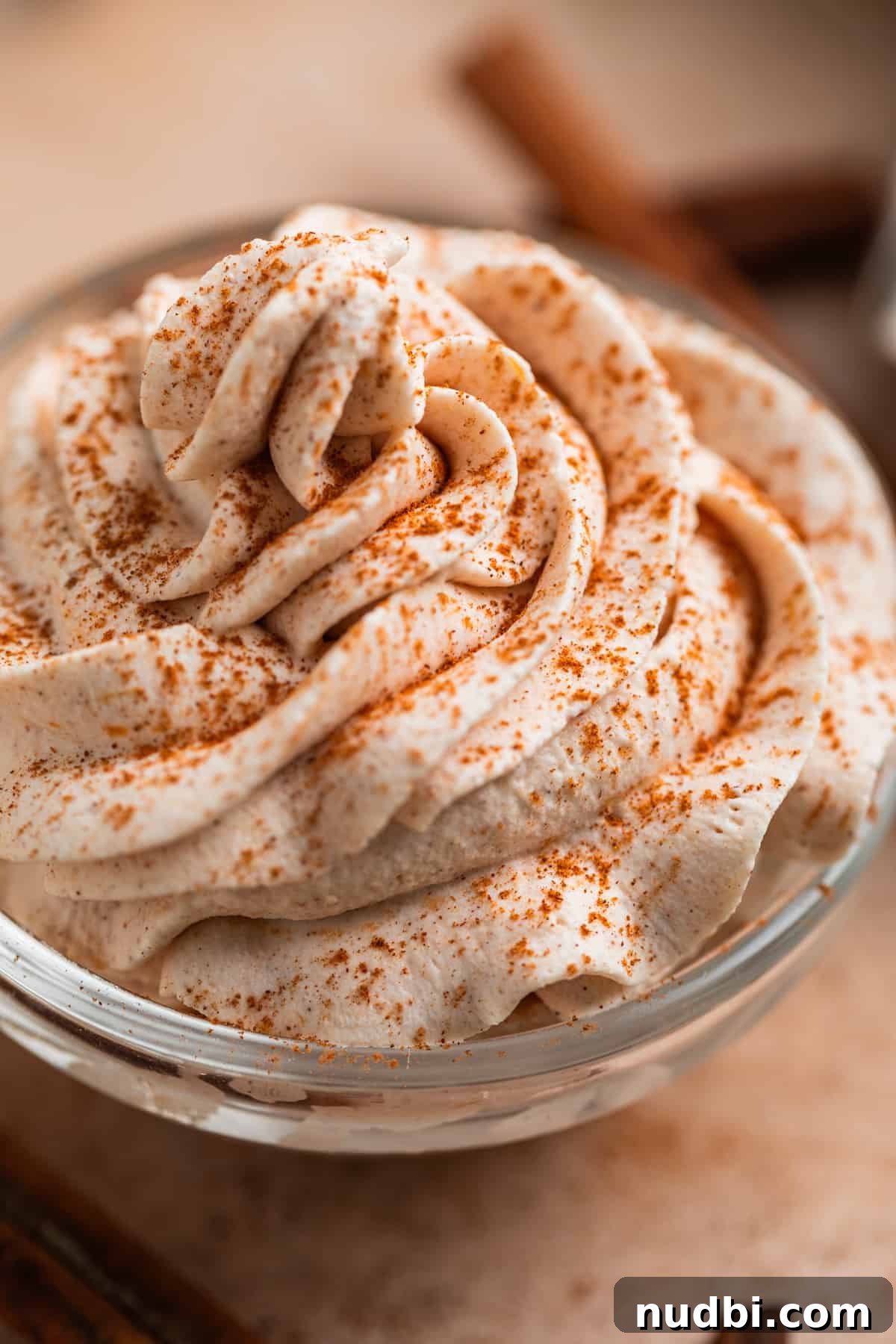 Pumpkin Spice Whipped Cream Recipe — Light & Fluffy Topping 7 Pumpkin spiced whipped cream piped in glass bowl.