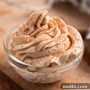 Pumpkin Spice Whipped Cream Recipe — Light & Fluffy Topping 9 Pumpkin spice whipped cream piped in glass bowl with cinnamon dusted over top.