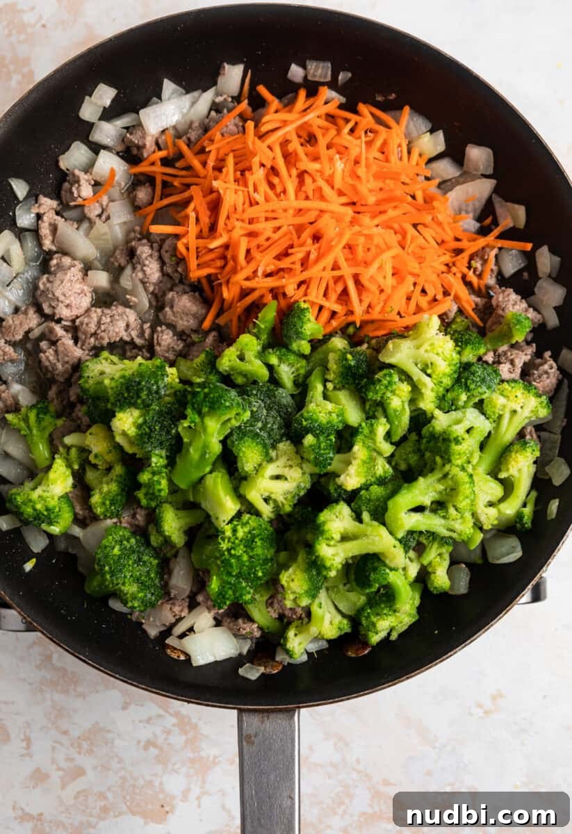 Savory Teriyaki Ground Pork Stir-Fry with Vegetables 8 Frozen broccoli and shredded carrots added over top meat and onion mixture in skillet.