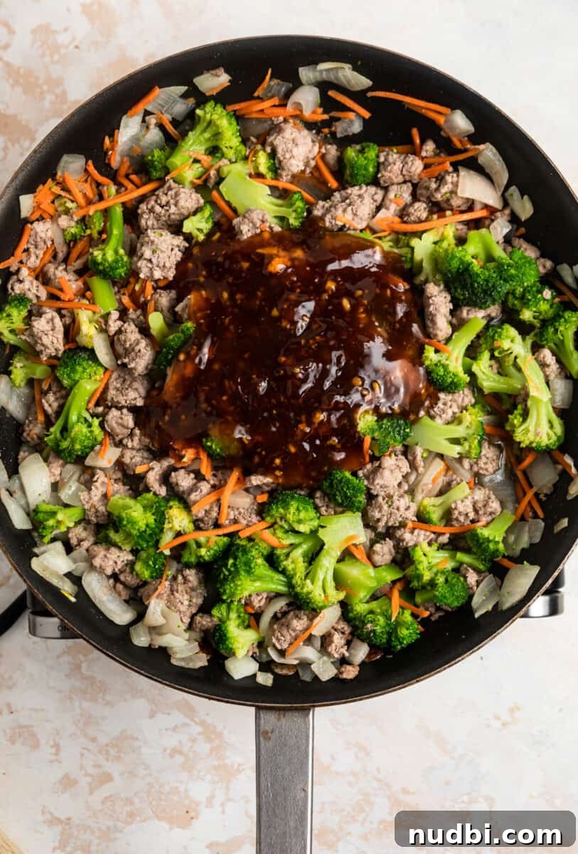 Savory Teriyaki Ground Pork Stir-Fry with Vegetables 9 Teriyaki sauce added to ground pork stir fry in skillet.