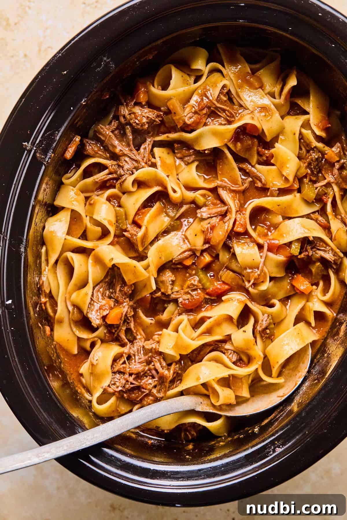 Slow-Cooked Short Rib Ragu Recipe for Tender Pasta Nights 11 Pappardelle pasta tossed in slow cooker short rib ragu mixture in pot.
