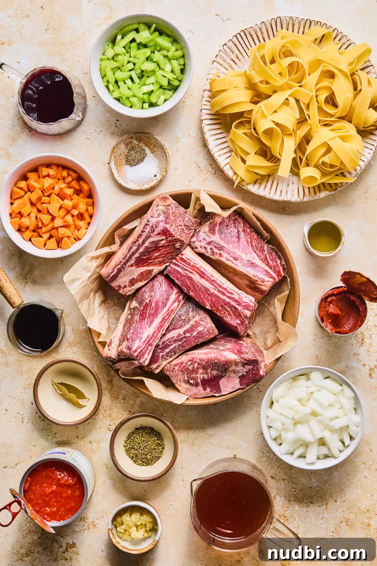 Slow-Cooked Short Rib Ragu Recipe for Tender Pasta Nights 3 Meat, vegetables, pasta and seasoning arranged on surface to make recipe.