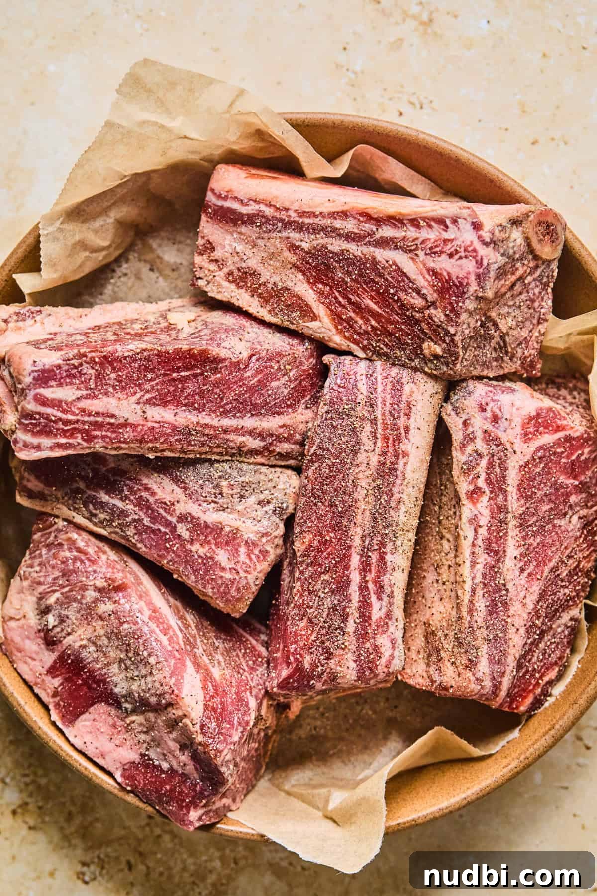 Slow-Cooked Short Rib Ragu Recipe for Tender Pasta Nights 4 Seasoned short ribs on parchment lined dish.