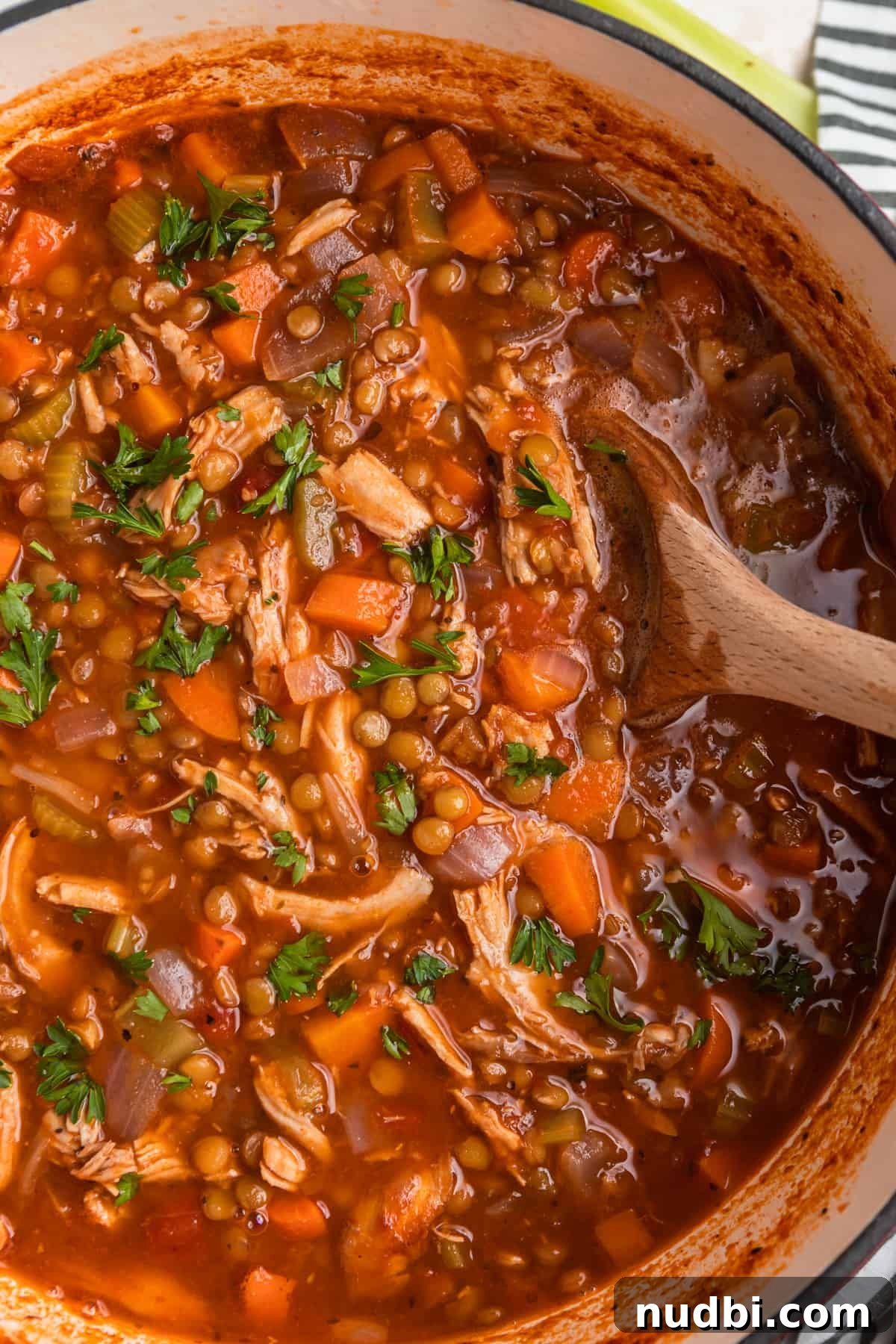 Hearty Turkey and Lentil Soup Recipe for Weeknight Dinners 2 Turkey lentil soup in pot with wooden spoon.