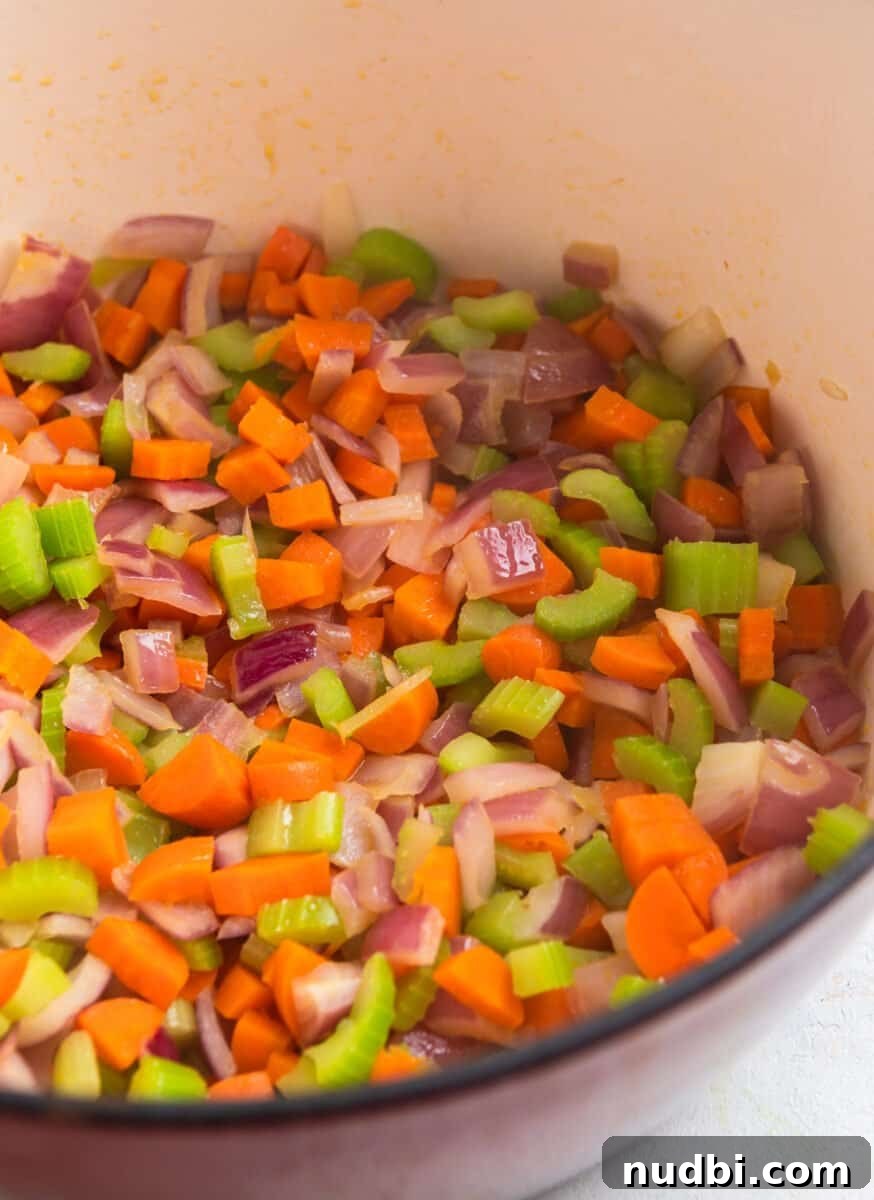 Hearty Turkey and Lentil Soup Recipe for Weeknight Dinners 4 Cooked carrots, celery and onion in red dutch oven.