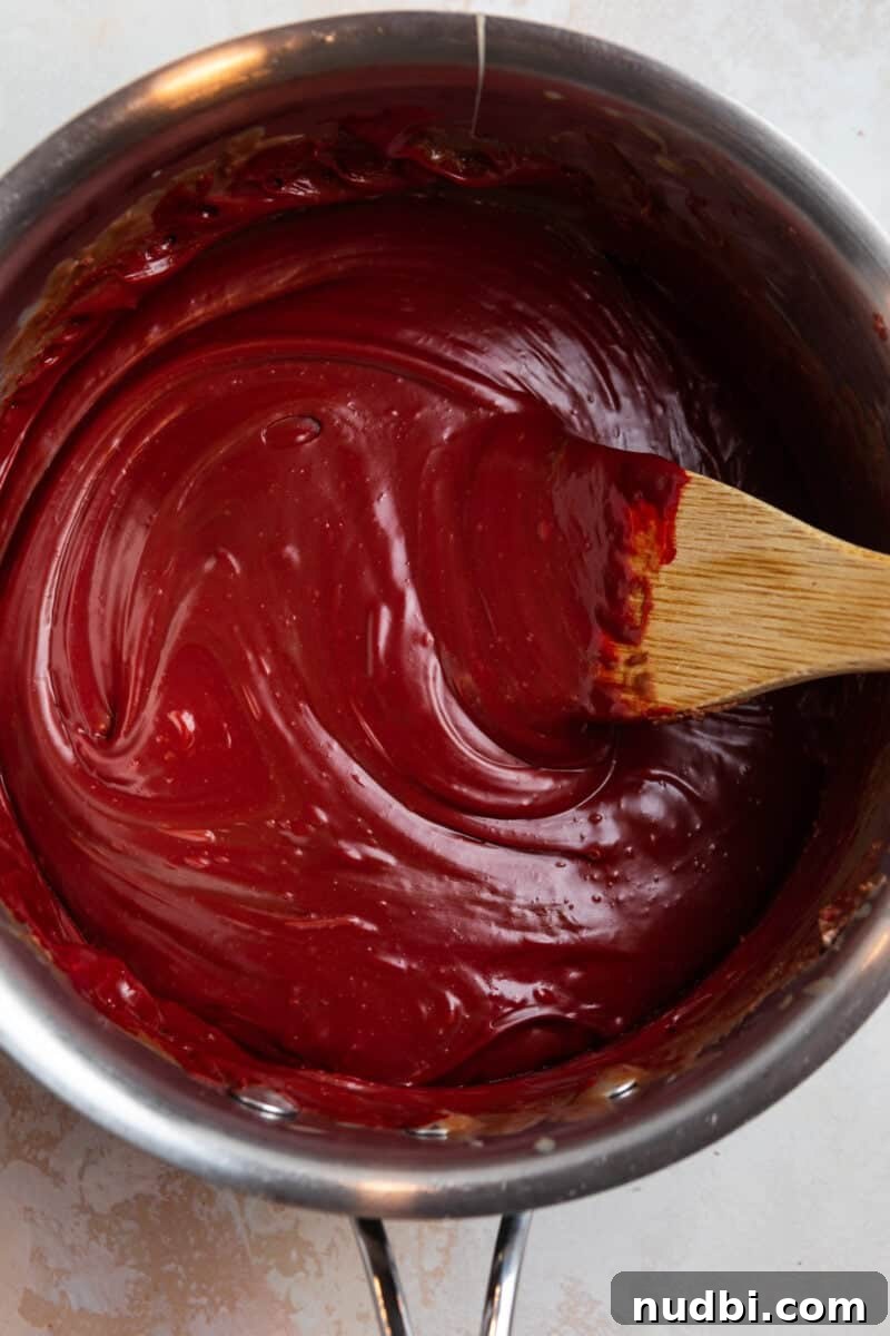 Decadent Red Velvet Oreo Fudge Recipe for Chocolate Lovers 6 Red velvet fuge prepped in sauce pan with wooden spoon.