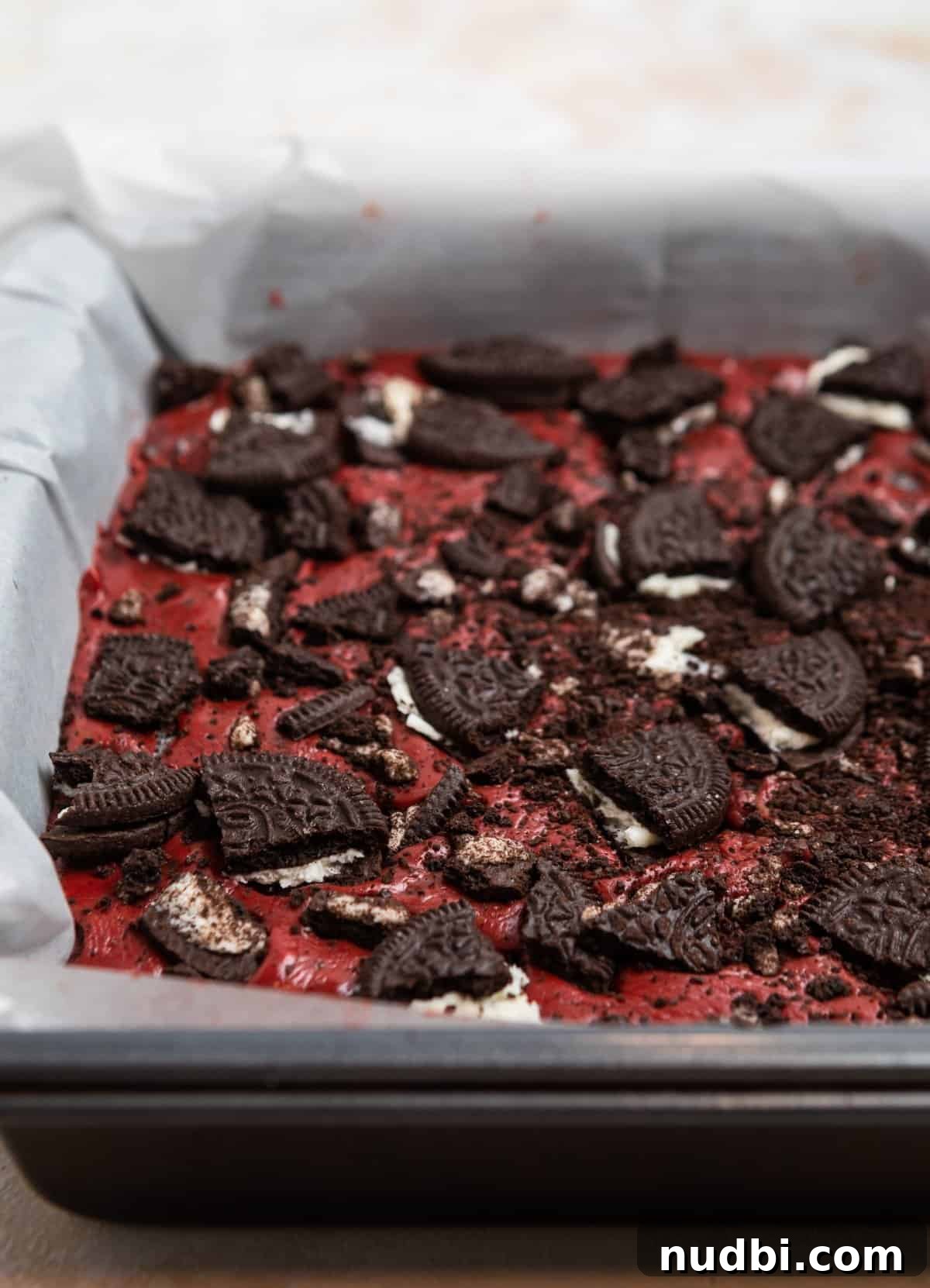 Decadent Red Velvet Oreo Fudge Recipe for Chocolate Lovers 8 Oreo red velvet fudge in parchment lined pan and topped with crushed Oreos.