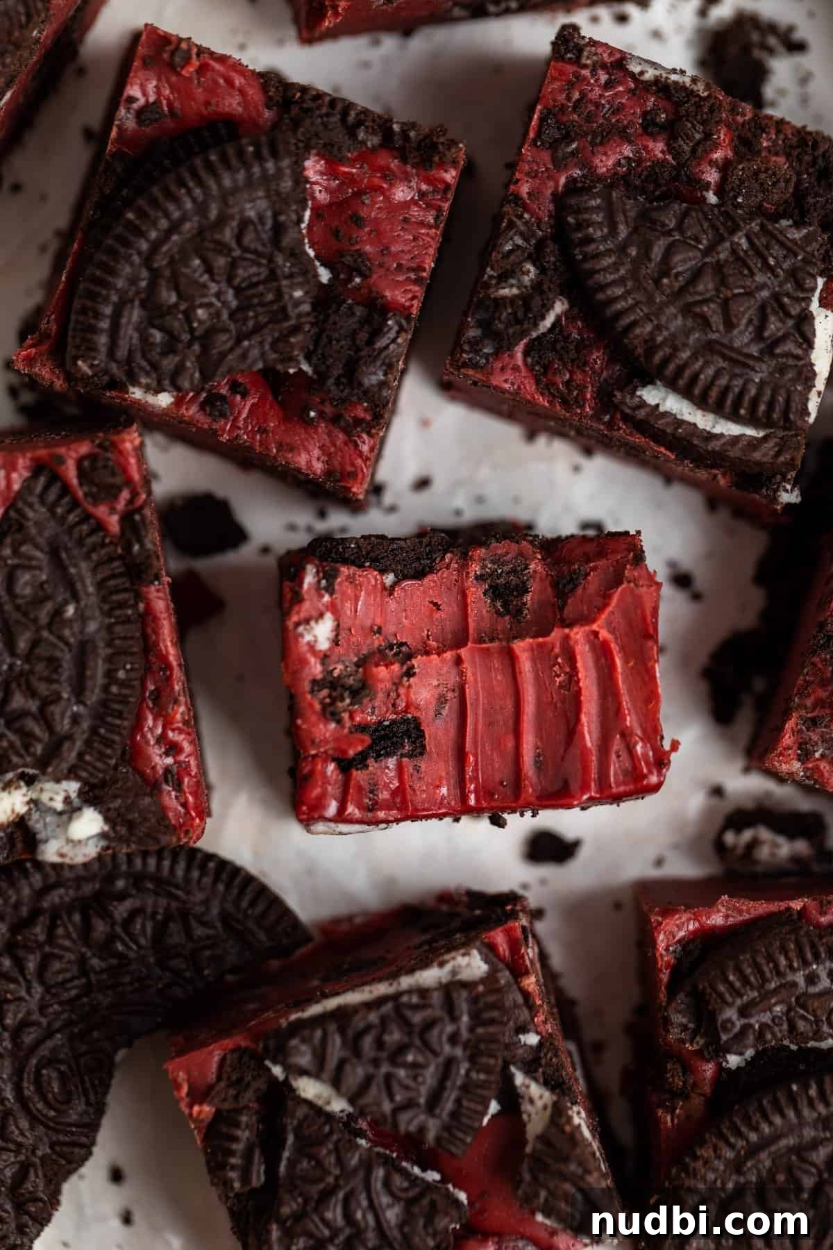 Decadent Red Velvet Oreo Fudge Recipe for Chocolate Lovers 9 Bite taken out of Oreo red velvet fudge piece surrounded by other pieces of fudge.