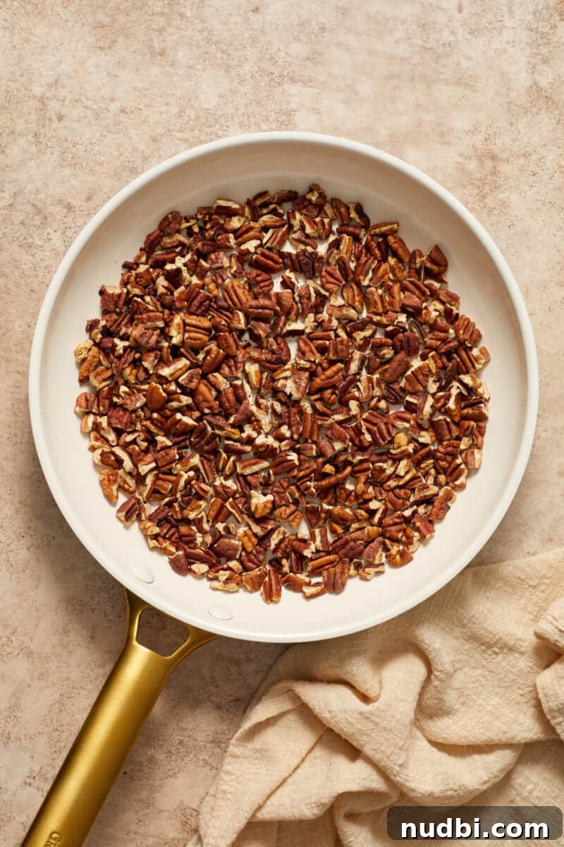 Chewy Chocolate Chip Pecan Cookies Recipe 4 Chopped pecans in skillet with tan linen beside it.