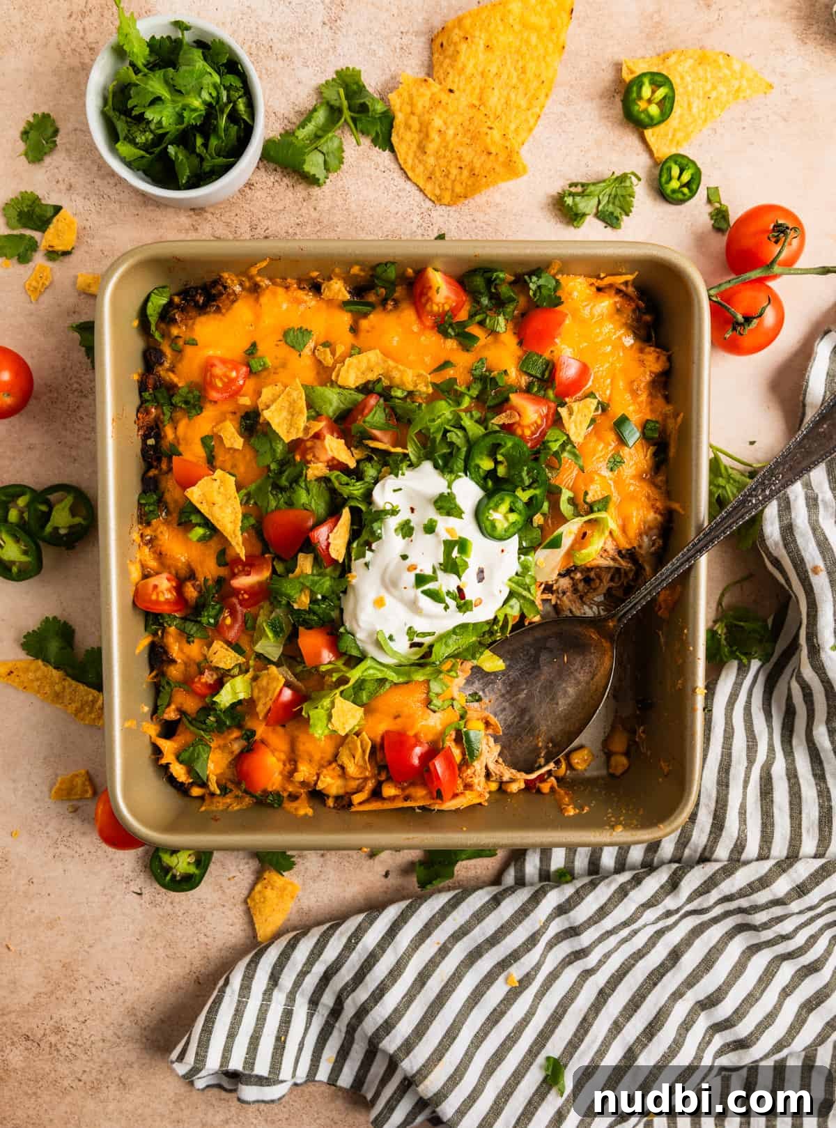 Cheesy Chicken Taco Casserole Bake with Crispy Tortilla Topping 2 Overhead view of chicken taco casserole in baking pan topped with lettuce, tomato, sour cream and cilantro.