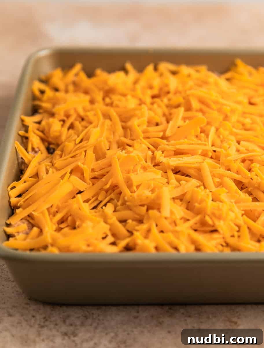 Cheesy Chicken Taco Casserole Bake with Crispy Tortilla Topping 6 Cheese topped mixture in baking pan on surface.