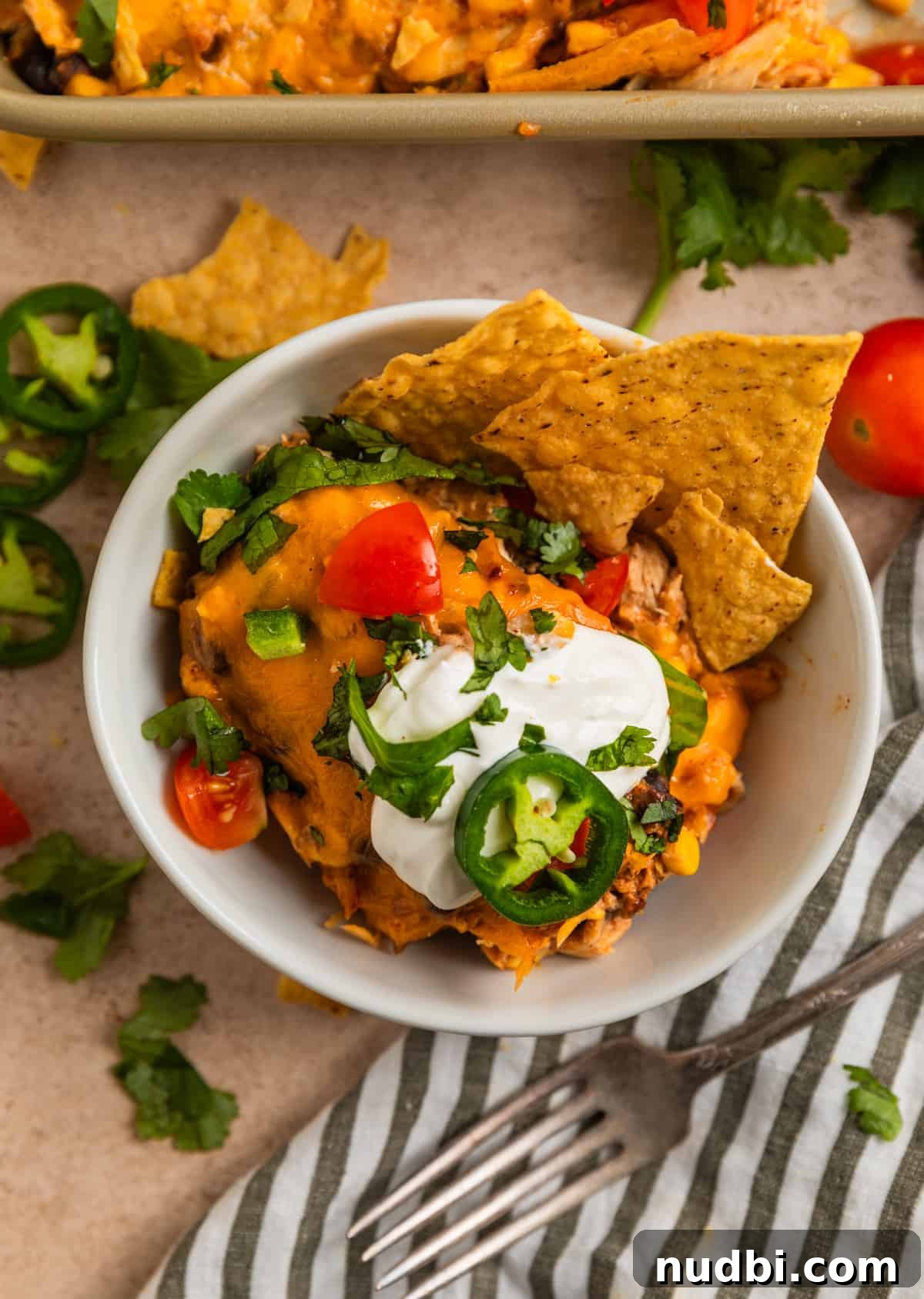 Cheesy Chicken Taco Casserole Bake with Crispy Tortilla Topping 8 Chicken taco mixture in bowl topped with sour cream, cilantro, tomatoes and jalapeño.